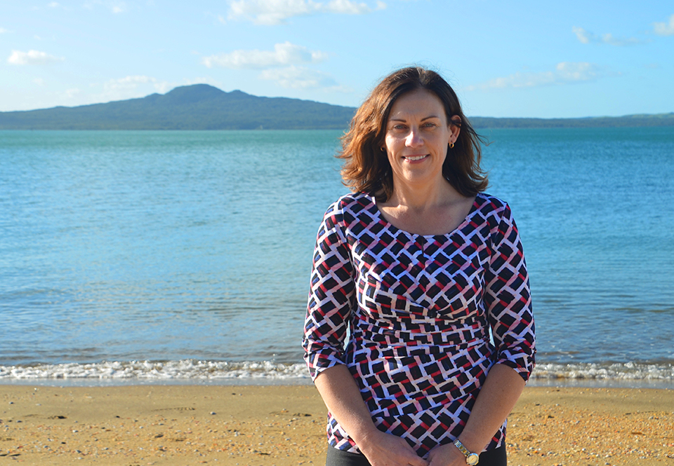 Tanya from MoaTrek on the beach in Auckland, Rangitoto Island behind