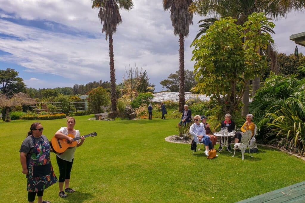 Two people with a guitar singing waiata on the lawn.